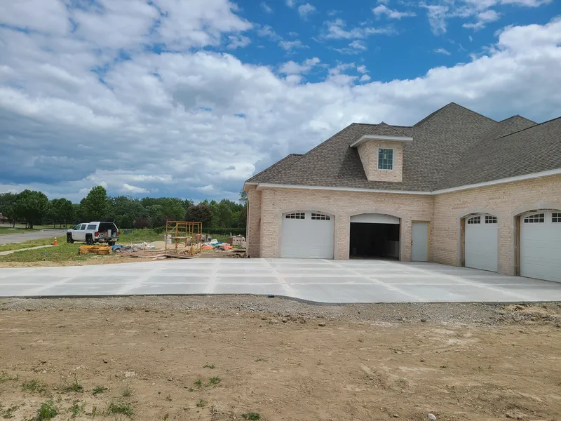 Concrete driveway approaching the attached garage of a brick home