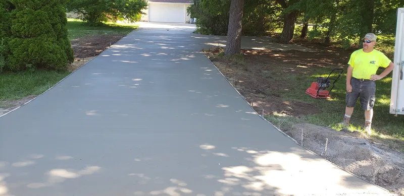 Merchant American Concrete crew member beside a newly poured residential driveway in Mid-Michigan