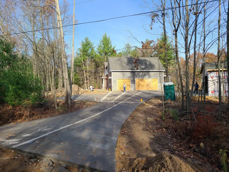 Curved concrete driveway on a tree-lined wooded property