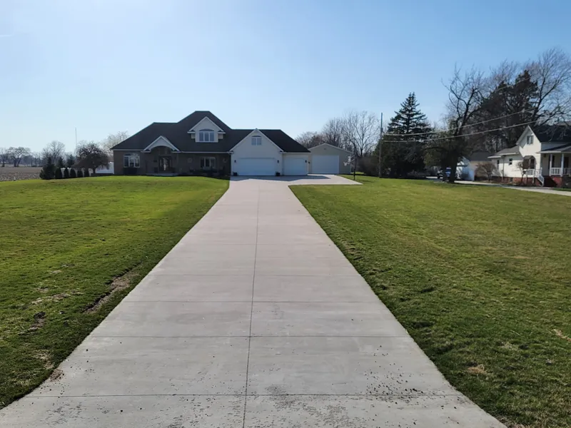 Wide concrete driveway approach to a two-story brick estate near Midland, Michigan
