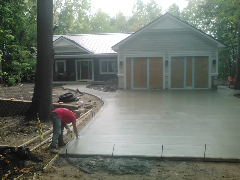 Crew forming and prepping a concrete driveway at a wooded home site