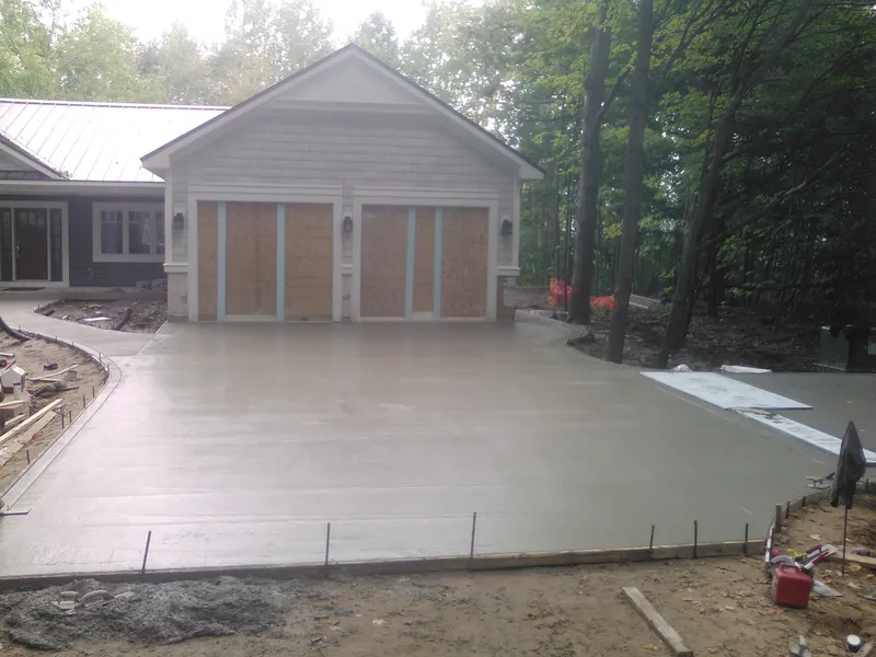 Concrete driveway to a modern home on a wooded lot