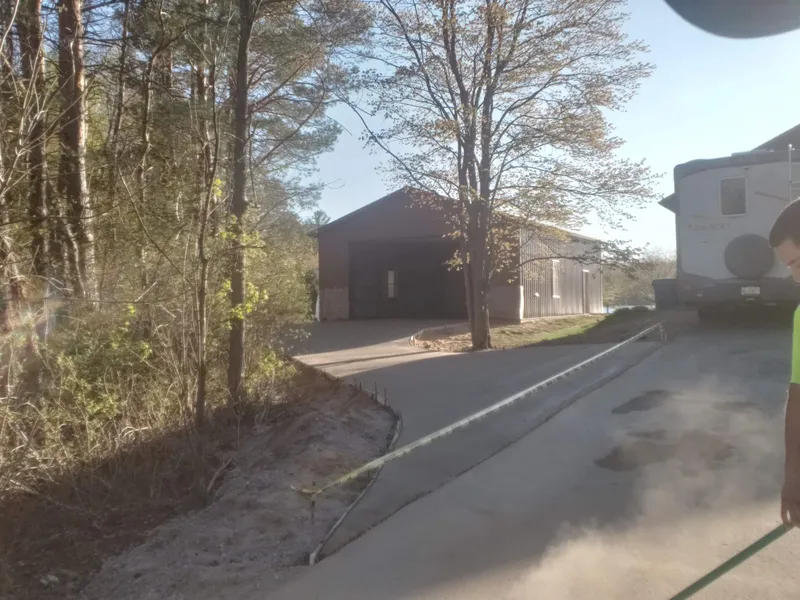 Long concrete driveway leading back to a pole barn on a rural property