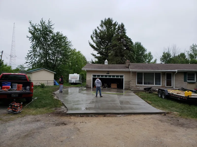 Freshly finished wet concrete driveway curing in front of a Mid-Michigan home
