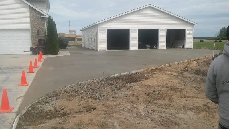 Concrete driveway leading to a white three-bay garage