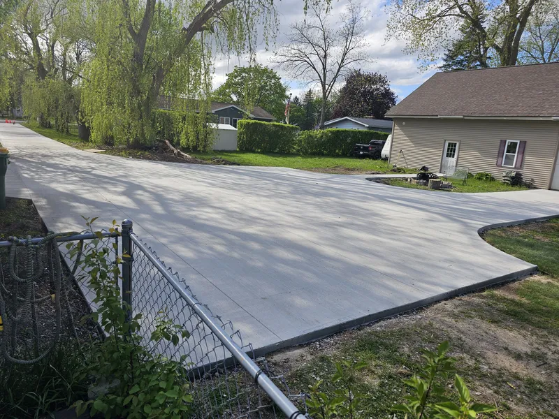 Wide concrete driveway beside a chain-link fenced yard