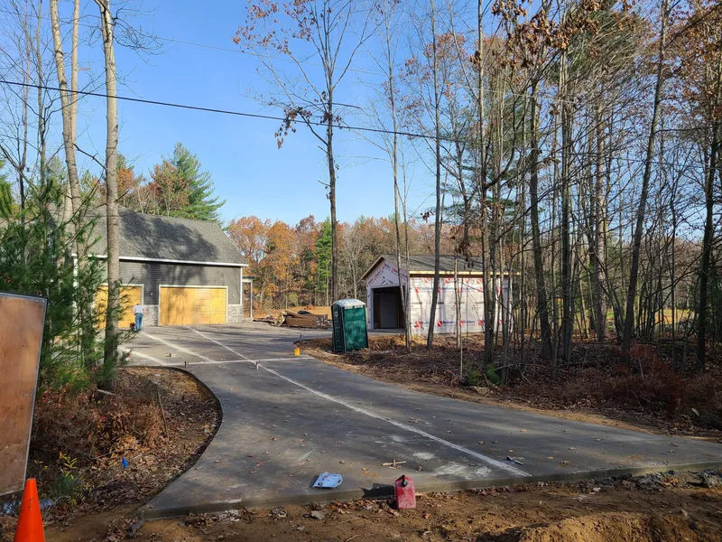 Concrete driveway winding through a wooded Mid-Michigan lot