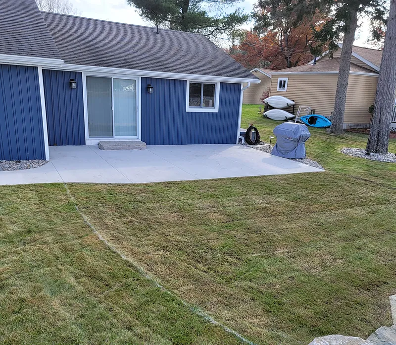Rear concrete patio behind a blue-sided Mid-Michigan home