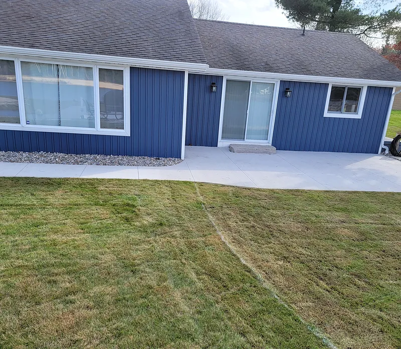 Concrete patio at the sliding-door entry of a blue home