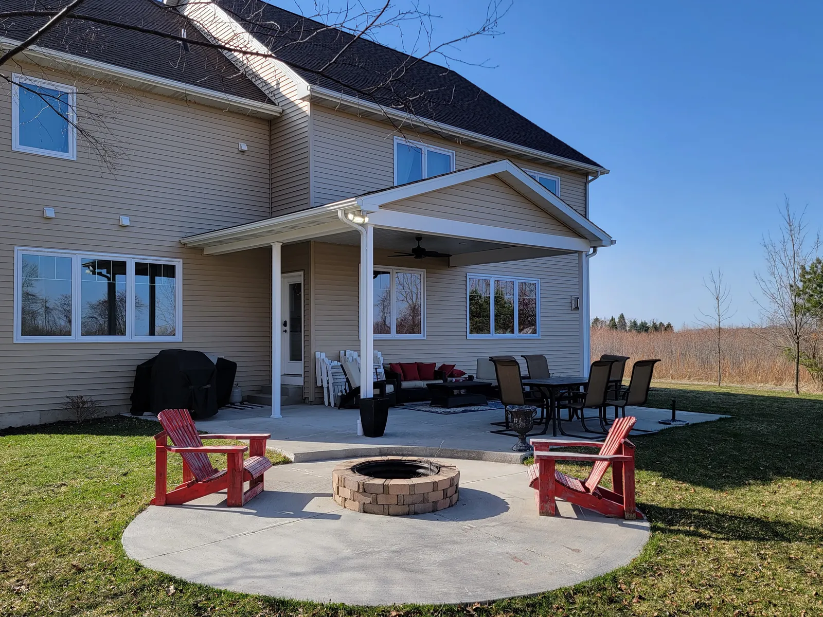 Concrete patio with built-in fire pit and seating behind a Mid-Michigan home