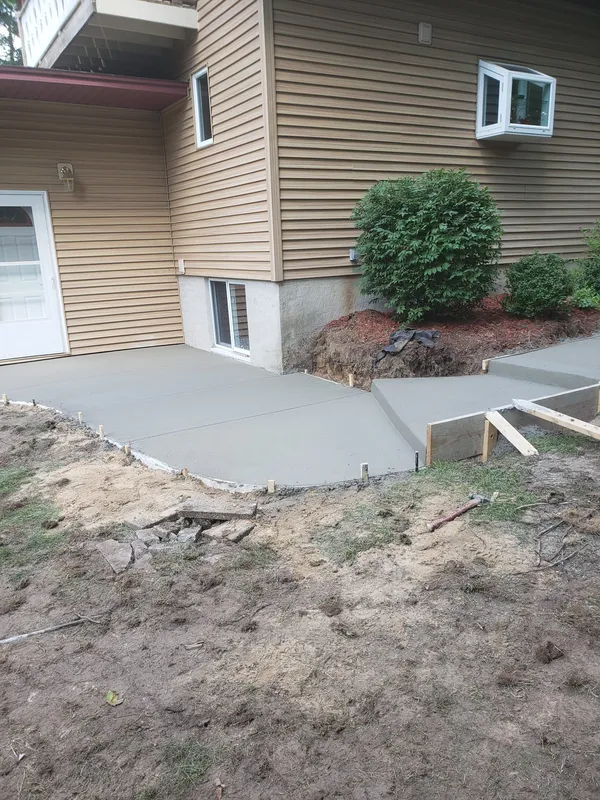 Rear concrete patio and walkway behind a residential home