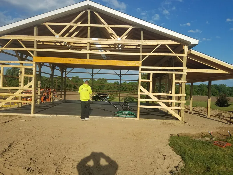Wet concrete pole barn floor being placed inside a new post-frame building