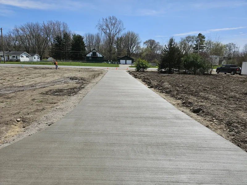 Wide concrete walkway poured across a residential yard