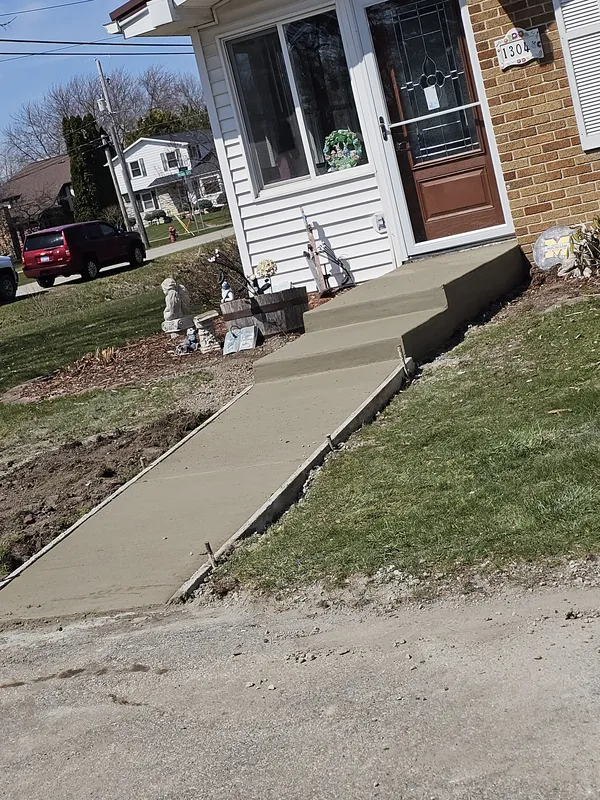 Concrete sidewalk with steps leading to a brick home entry